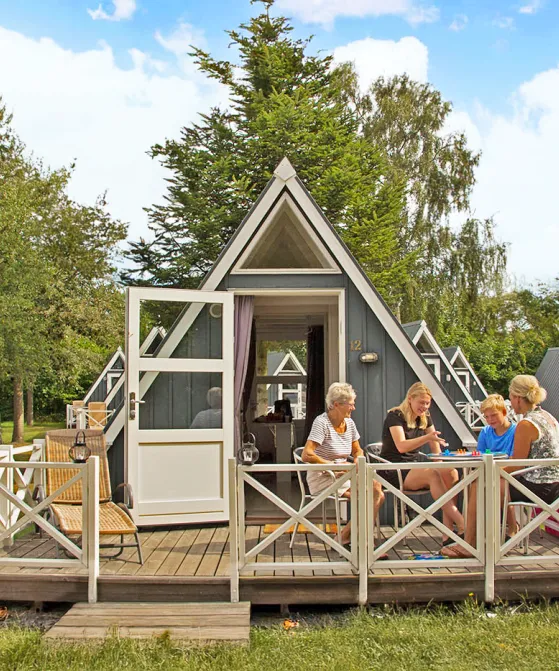 Familie hygger sig med brætspil på terrasse i Hasle Hytteby