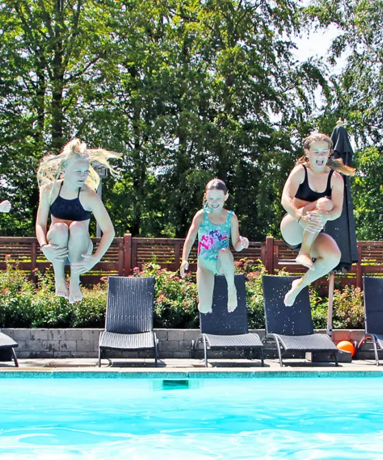 Fem børn og unge hopper i poolen ved Hasle Hytteby og Feriepark
