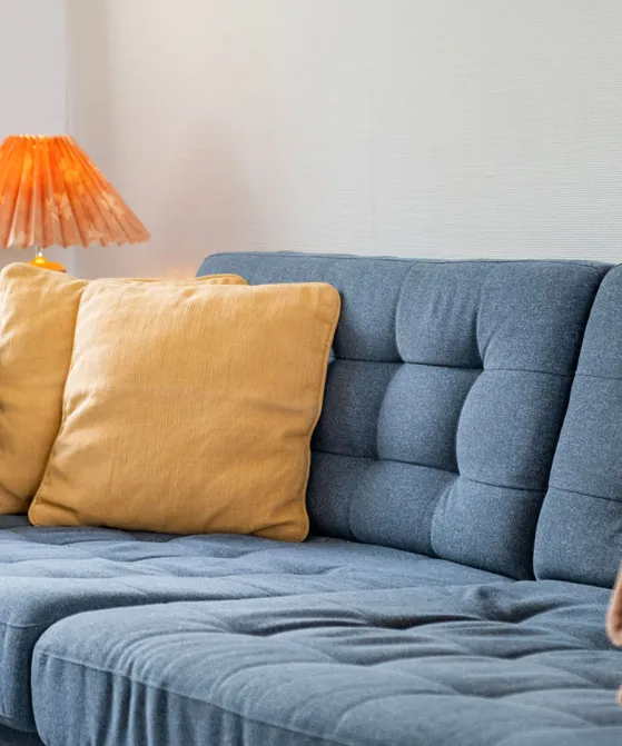 Sofa med gule pyntepuder og tæppe i ferielejlighed Gnisten