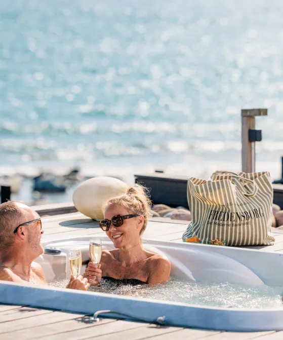 Par nyder et glas bobler i udendørs jacuzzi på Fredensborg Badehotel