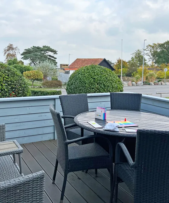 Terrasse med havemøbler og havglimt i Friheden Ferielejligheder