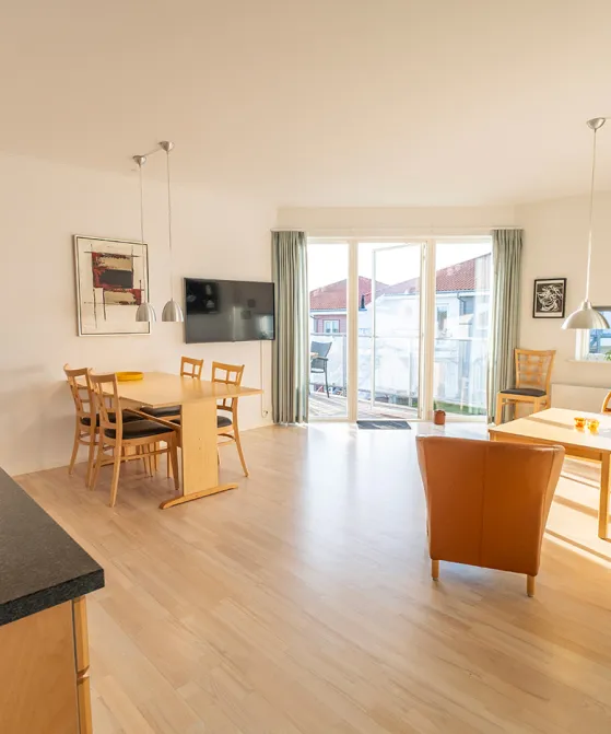 Opholdsrum med køkken, stue og udgang til terrasse i Gudhjem Søpark