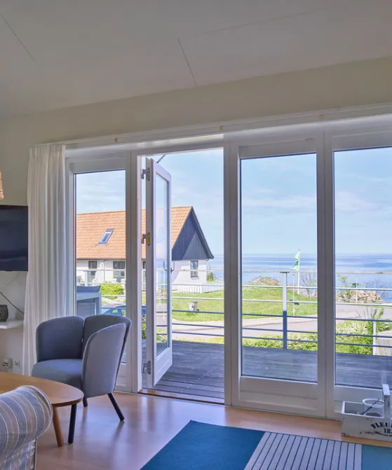Opholdsrum med udgang til terrasse med havudsigt i Gudhjem Feriehuse