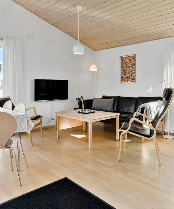 Lyst opholdsrum med sofahjørne og spiseplads i Rø Golfhuse