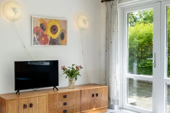 TV-hjørne med fladskærm og kunst på væggen i ferielejlighed Gnisten