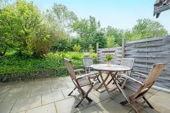 Terrasse med havemøbler i grønne omgivelser i ferielejlighed Gnisten