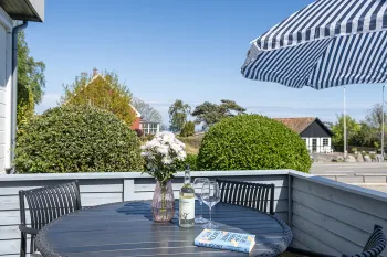 Terrasse med havemøbler og grill i grønne omgivelser i Friheden Ferielejligheder