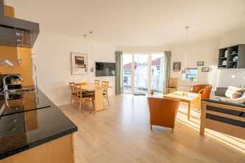 Opholdsrum med køkken, stue og udgang til terrasse i Gudhjem Søpark