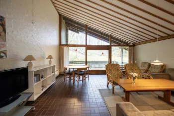 Stor stue med sofa, tv og udgang til overdækket terrasse i Hammershuse 1C