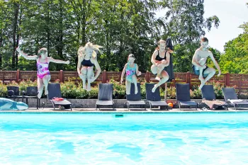 Fem børn og unge hopper i poolen ved Hasle Hytteby og Feriepark