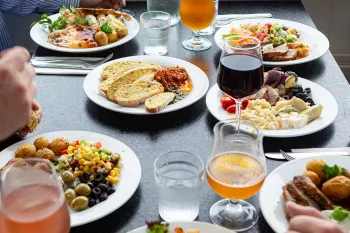 Middagsborg med tallerkner med mad fra buffeten og glas med vin på Abildgaard All-Inclusive