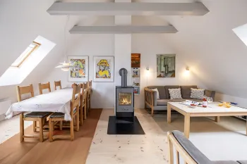 Hyggelig opholdsrum med sofaer, brændeovn og spiseplads i Smedjen 