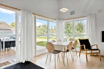 Lys opholdsstue med udgang til træterrasse i feriehus i Rø Golfhuse