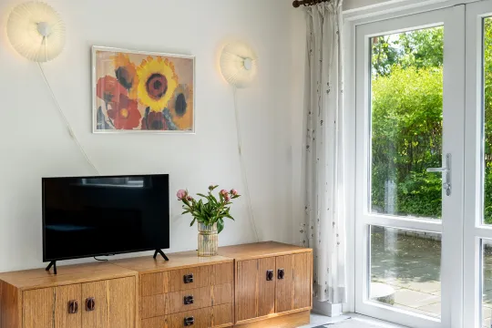 TV-hjørne med fladskærm og kunst på væggen i ferielejlighed Gnisten