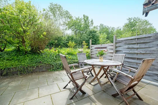 Terrasse med havemøbler i grønne omgivelser i ferielejlighed Gnisten