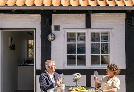 Par nyder solskinstimerne på terrasse ved ferielejlighed på Munken