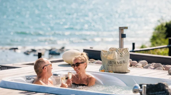 Par nyder et glas bobler i udendørs jacuzzi på Fredensborg Badehotel
