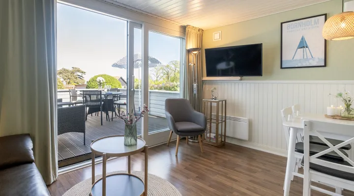 Stue med TV, bløde møbler og udgang til egen terrasse i Friheden Ferielejligheder