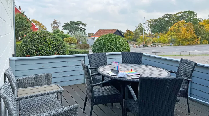 Terrasse med havemøbler og havglimt i Friheden Ferielejligheder