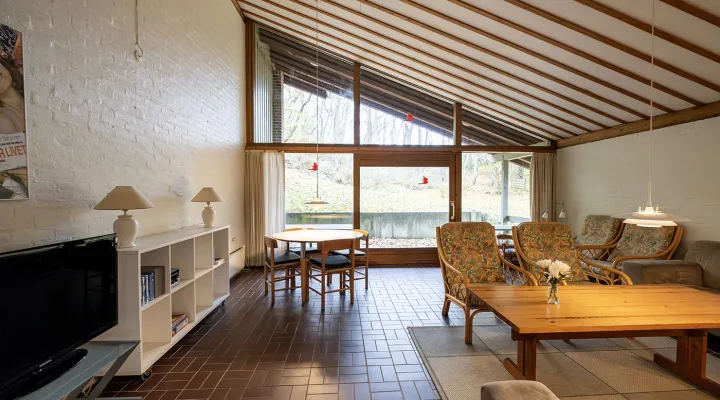 Stor stue med sofa, tv og udgang til overdækket terrasse i Hammershuse 1C