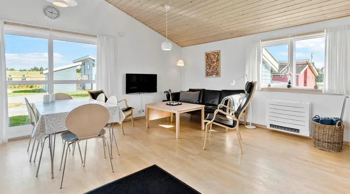 Lyst opholdsrum med sofahjørne og spiseplads i Rø Golfhuse