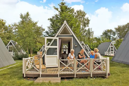 Familie hygger sig med brætspil på terrasse i Hasle Hytteby