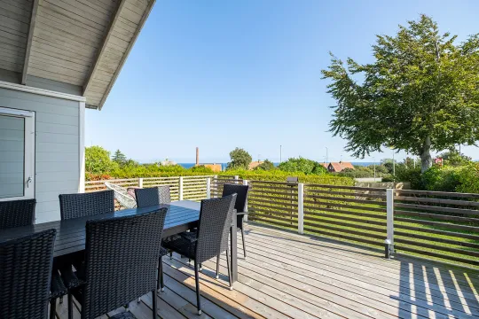Stor træterrasse med havemøbler og kig til havet i Bornhamas