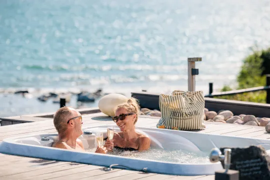 Par nyder et glas bobler i udendørs jacuzzi på Fredensborg Badehotel
