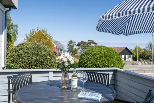 Terrasse med havemøbler og grill i grønne omgivelser i Friheden Ferielejligheder