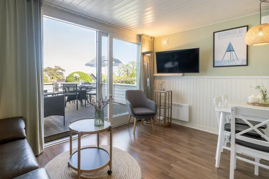 Stue med TV, bløde møbler og udgang til egen terrasse i Friheden Ferielejligheder