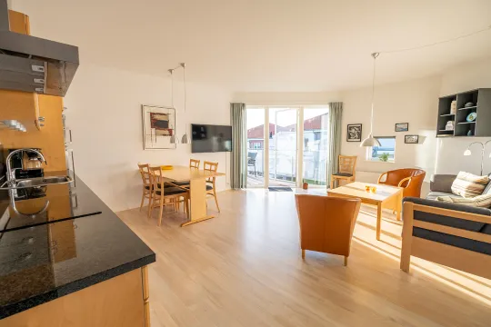 Opholdsrum med køkken, stue og udgang til terrasse i Gudhjem Søpark