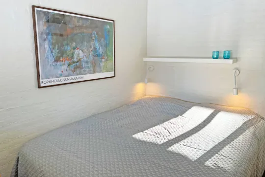 Dobbeltseng i det ene soveværelse i feriehus for 4 personer med havudsigt i Hammershuse