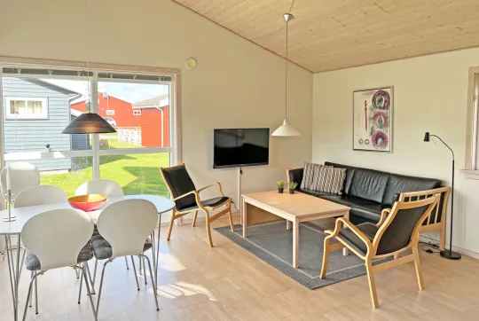 Opholdsrum med spiseplads, sofa og tv i feriehus i Rø Golfhuse