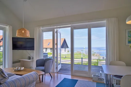 Opholdsrum med udgang til terrasse med havudsigt i Gudhjem Feriehuse