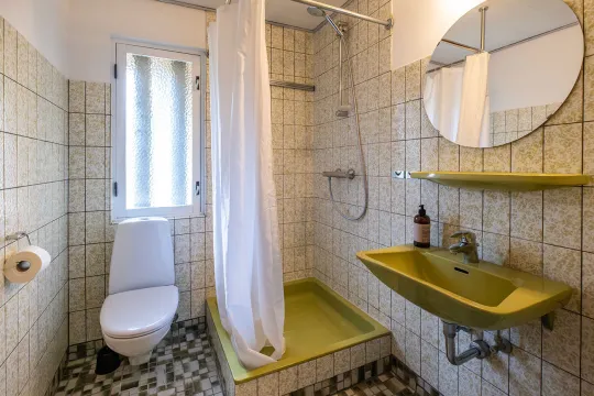 Badeværelse med wc, brus og håndvask i stueetagen i Villa Bølshavn